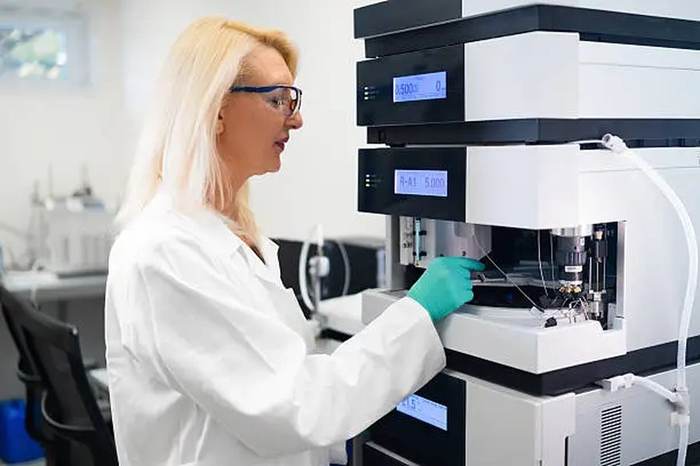 Scientist operating HPLC instrument in accredited laboratory